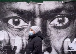 A woman in a protective mask walks past the banner
