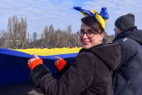 Protesters hold an unfurled flag of Ukraine
