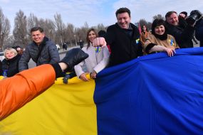 Protesters hold an unfurled flag of Ukraine