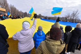 Protesters hold an unfurled flag of Ukraine