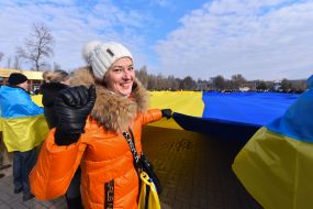 Protesters hold an unfurled flag of Ukraine