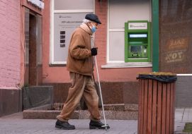An elderly man walks near an ATM