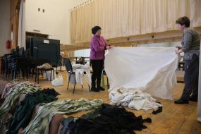 Women cut fabric for camouflage suits