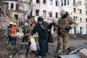 A serviceman of the Terrorist Defense Forces takes a woman out of a house destroyed after the shelling by the Russian military occupiers