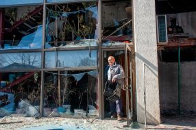 A man is standing near a house in Kharkiv destroyed by shelling