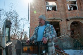 A man is standing near a house in Kharkiv destroyed by shelling