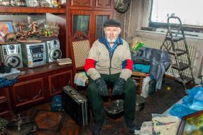 An elderly man in his ruined apartment