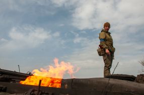 A Ukrainian soldier stands on a burning tank of the Russian occupiers