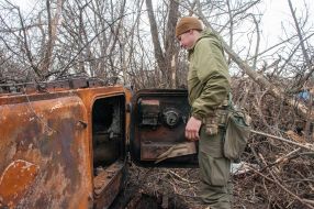 A Ukrainian soldier inspects a downed MT-LB artillery tractor of the Russian occupiers