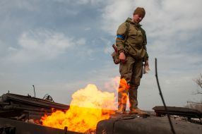 A Ukrainian soldier stands on a burning tank of the Russian occupiers