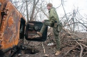 A Ukrainian soldier inspects a downed MT-LB artillery tractor of the Russian occupiers