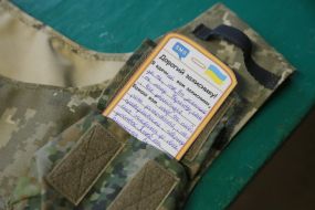 Volunteer puts thank you card to the soldiers in a body armor case in a sewing shop in Stryi