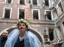 Волонтеры Настя и Антон в день своей свадьбы фотографируются на фоне разрушенных домов