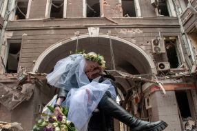 Волонтеры Настя и Антон в день своей свадьбы фотографируются на фоне разрушенных домов