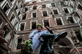 Волонтеры Настя и Антон в день своей свадьбы фотографируются на фоне разрушенных домов