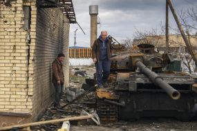 Men near the destroyed Russian tank in Gostomel