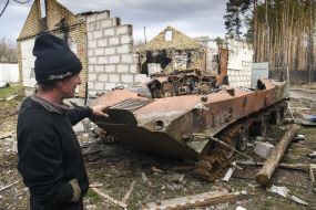 A man shows a destroyed Russian tank in Gostomel