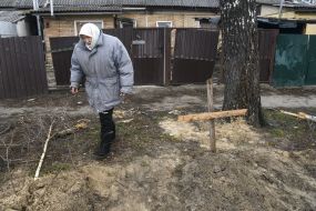 Woman near the grave with a wooden cross at the burial place in Gostomel