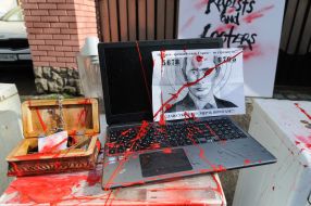 Laptop flooded with red paint and portrait of Putin with red paint near the building of the Russian consulate in Lviv