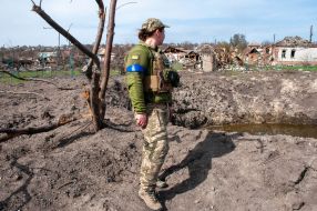 A woman - a fighter of the territorial defense near the houses destroyed as a result of shelling in Chuguev
