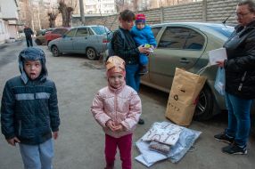 A woman walks with children in Kharkiv
