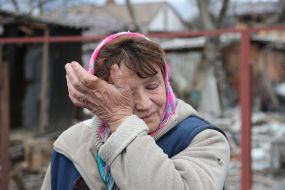 Жінка біля зруйнованого будинку