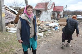 Жінка біля зруйнованого будинку