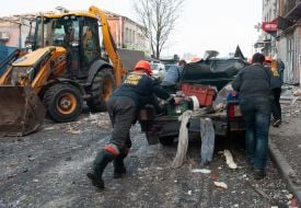 Utility workers push a car damaged in the R-500 "Caliber" missile in Kharkiv