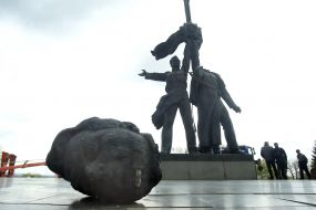The head of a Russian worker near the bronze sculpture of two workers under the arch of friendship of peoples in Kiev