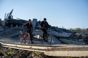 Cyclists pass by a blown up bridge