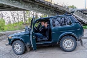 A car drives past a blown-up bridge