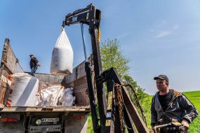 Farmer pouring fertilizer into tractor hopper on the field