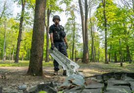 SES officer removes cluster munition remnants from fragment of Polish Memorial to Victims of Totalitarianism in Kharkiv