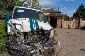 A wrecked police minibus stands near a destroyed house