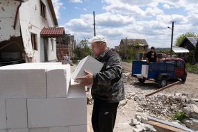 The man makes in the yard of the destroyed house building materials for restoration of the house in the village of Mala Rogan