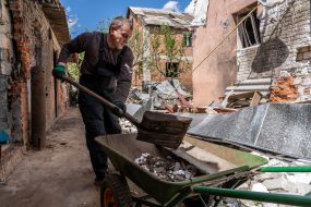 A man is raking up the rubble of his ruined house in the village of Mala Rohan