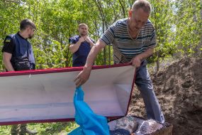 The volunteer opens the homeland during the exhumation of the body of a murdered resident of the village of Koropove