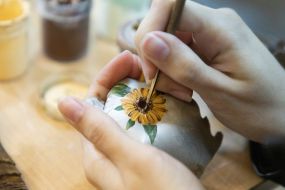 The artist paints a sunflower on the wreckage of a downed rocket