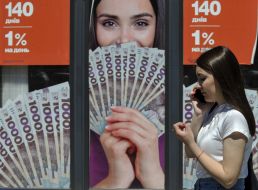 Женщина с мобильным телефоном на фоне рекламного стенда в Киеве