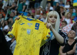 Болельщица держит футболку с автографами футболистов