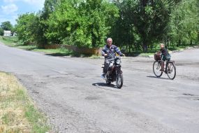 Elderly man on a motorcycle and a boy on a bicycle