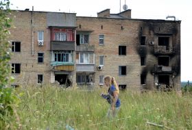 A girl against the background of a residential building in the village of Gorenka destroyed by shelling by Russian occupiers