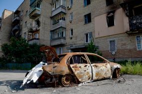 A burnt car near a residential building destroyed by shelling by Russian occupiers