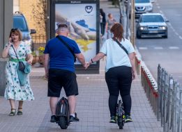 People ride unicycles holding hands