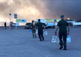 Rescuers carry bottles of water to the mall hit by a Russian missile