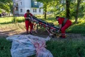 Медики забирають тіло вбитого чоловіка після обстрілу