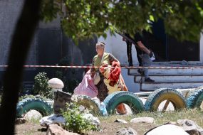 A woman with things near the recreation center in Serhiyivka, which was destroyed after a rocket attack by the Russian occupiers