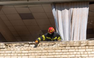 Rescuers clear the rubble of the building of a comprehensive school that collapsed as a result of a night hit by two rockets