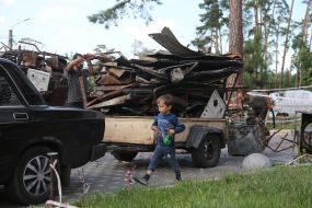 Men load scrap metal into a trailer in Irpen