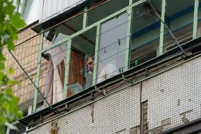 A man removes broken glass from the balcony of his apartment
